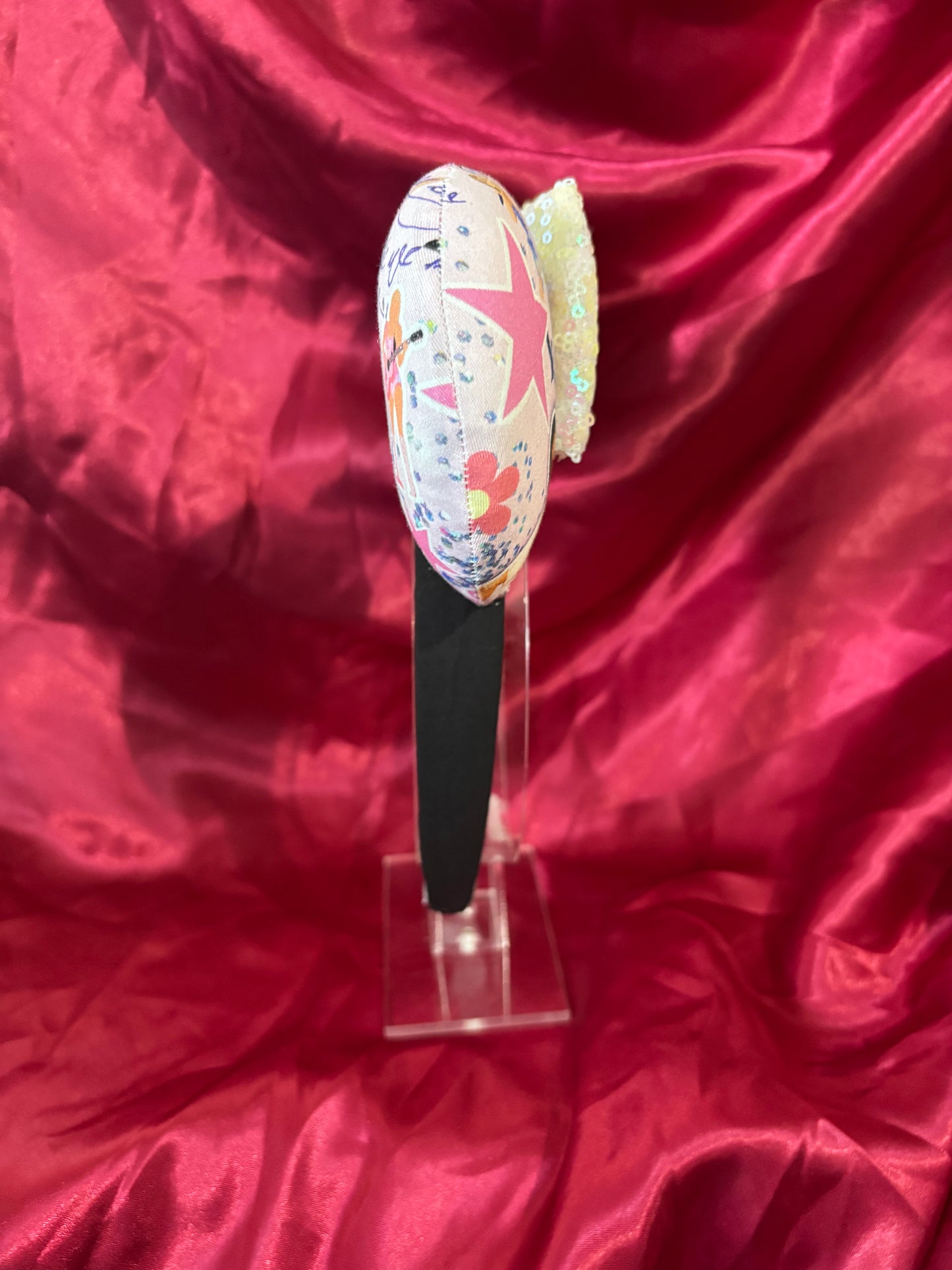 Mouse ears Headband with decorative elements. Shown on a pink glittery background