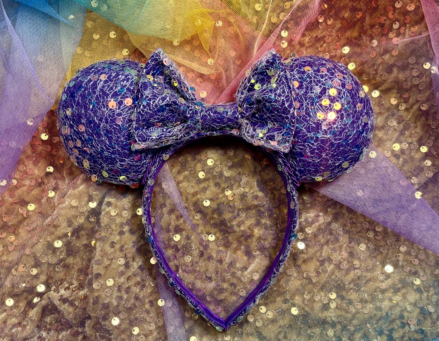 Purple sequin mouse ears on a rainbow background