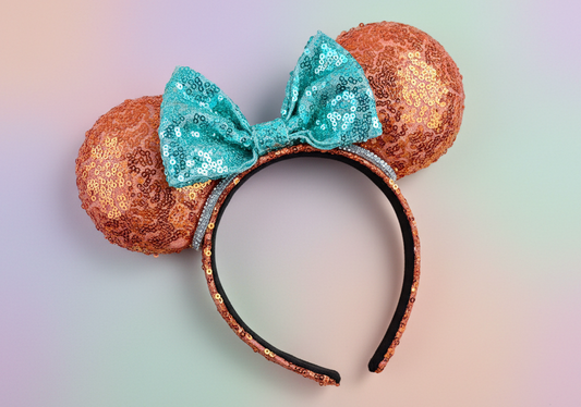 Sequin mouse ears with orang on ears and the headband with a mint bow and rhinestone trim. Shown on a gradient background