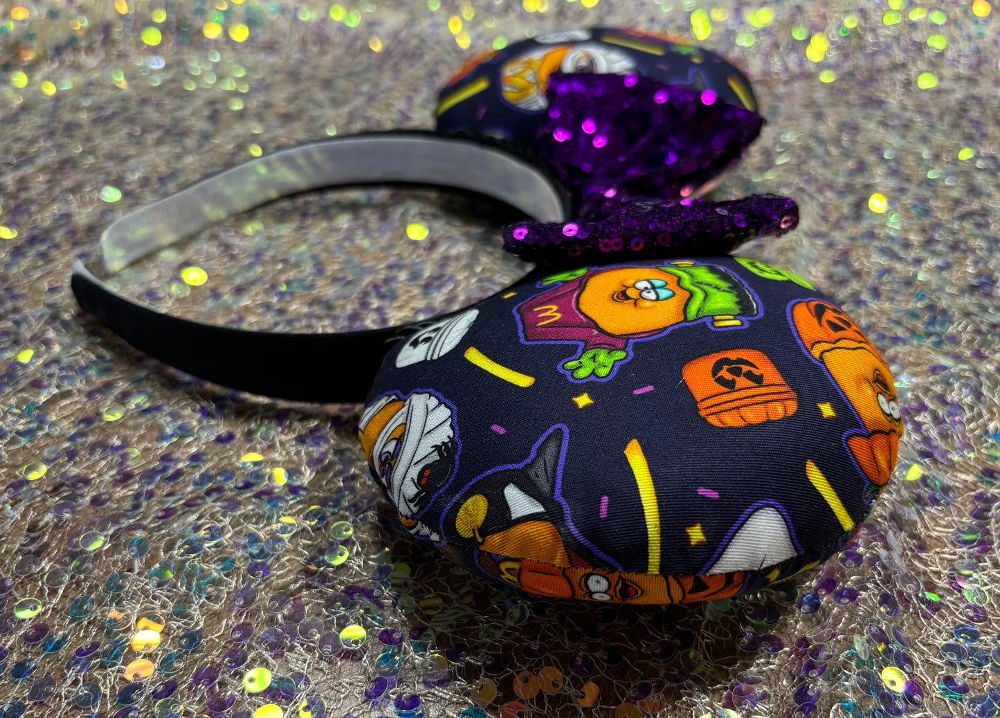 Handmade and ready to ship. The are some nostalgic chicken nuggets from the 90's in their Halloween costumes. The Halloween pals are on these are well. Attached to a black headband with a purple sequin bow. Shown on a white gliter background.