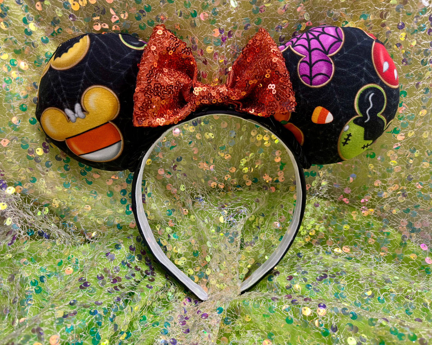 Halloween-themed mouse ears with a bow on a glittery background.