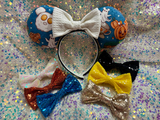 Handmade and ready to ship Fall Mouse ears with pumpkins, eggs, waffles and more shaped like mouse ears is on the front and back of mouse ears with a white waffle print bow on a rainbow glitter background.. Collection of colorful bows is also shown in case you prefer a sequin one. Just write me a note in your order and I will attach the bow you want.