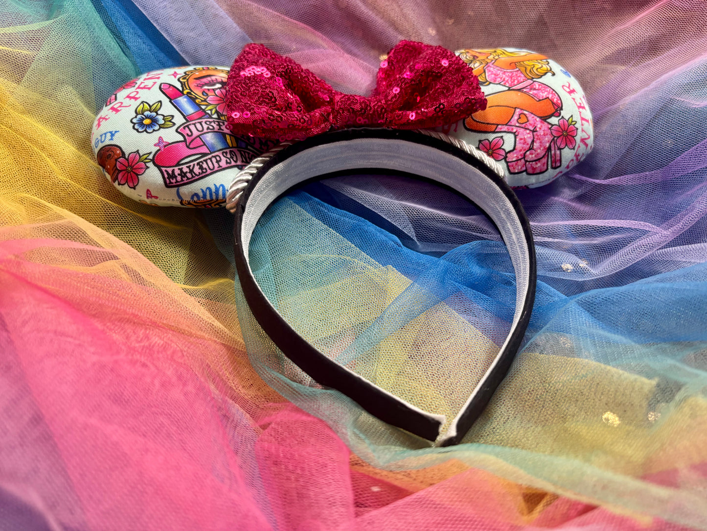 Cartoon SC-themed mouse ears on a black headband with a hot pink sequin bow. Shown on a colorful background