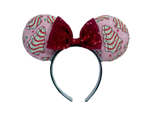 Handmade and ready to ship. Decorative headband with pink fabric and Christmas tree cake inspired fabric on the ears featuring a red sequin bow on a white background