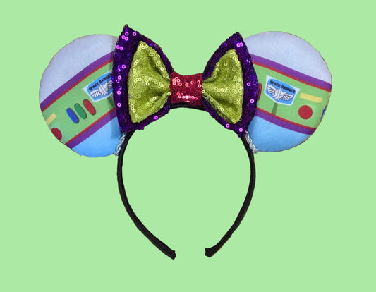 Space Ranger Mouse Ear headband with new improved bow. Handmade and ready to ship with Space ranger fabric on both the front and the back of mouse ears. The set has a silver twisted trim along the inner ears and a new sequin bow that is purple, lime green and red in sequin. Ears are on a black poly cotton universal sized headband.