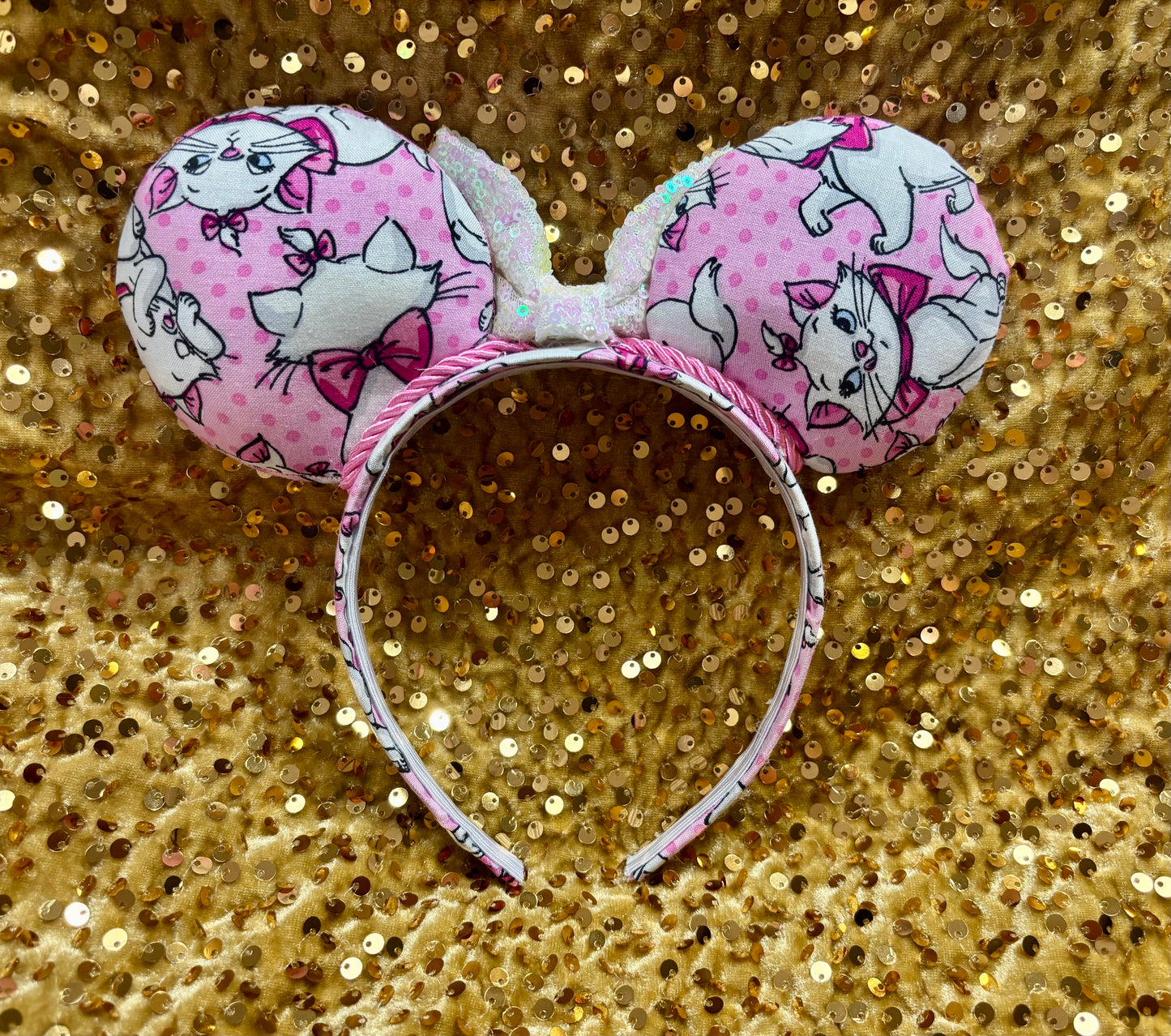 Pink mouse ear headband with white bow shown on a gold glitter background
