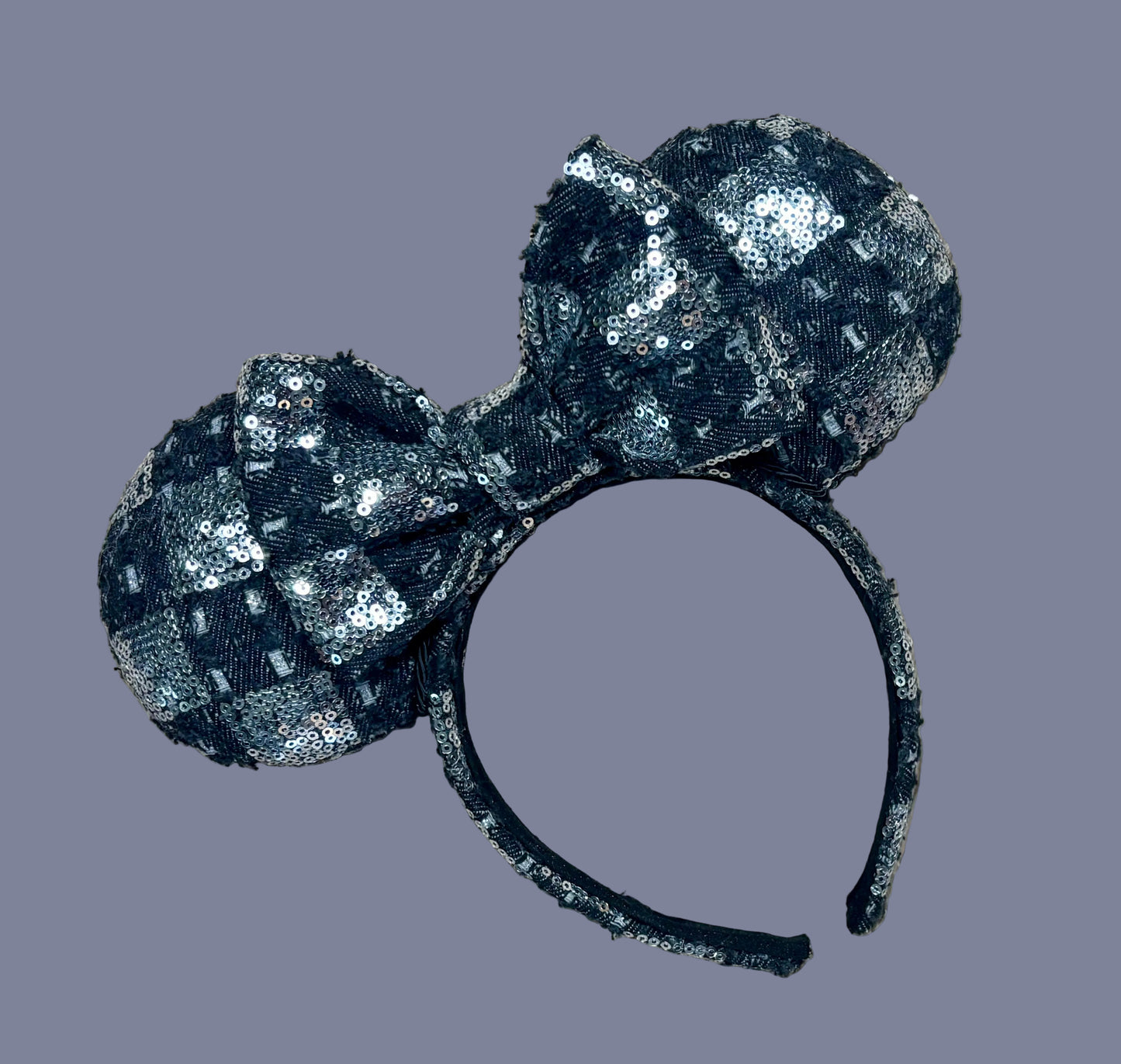 A black and silver checkered sequined headband with large bow ears.