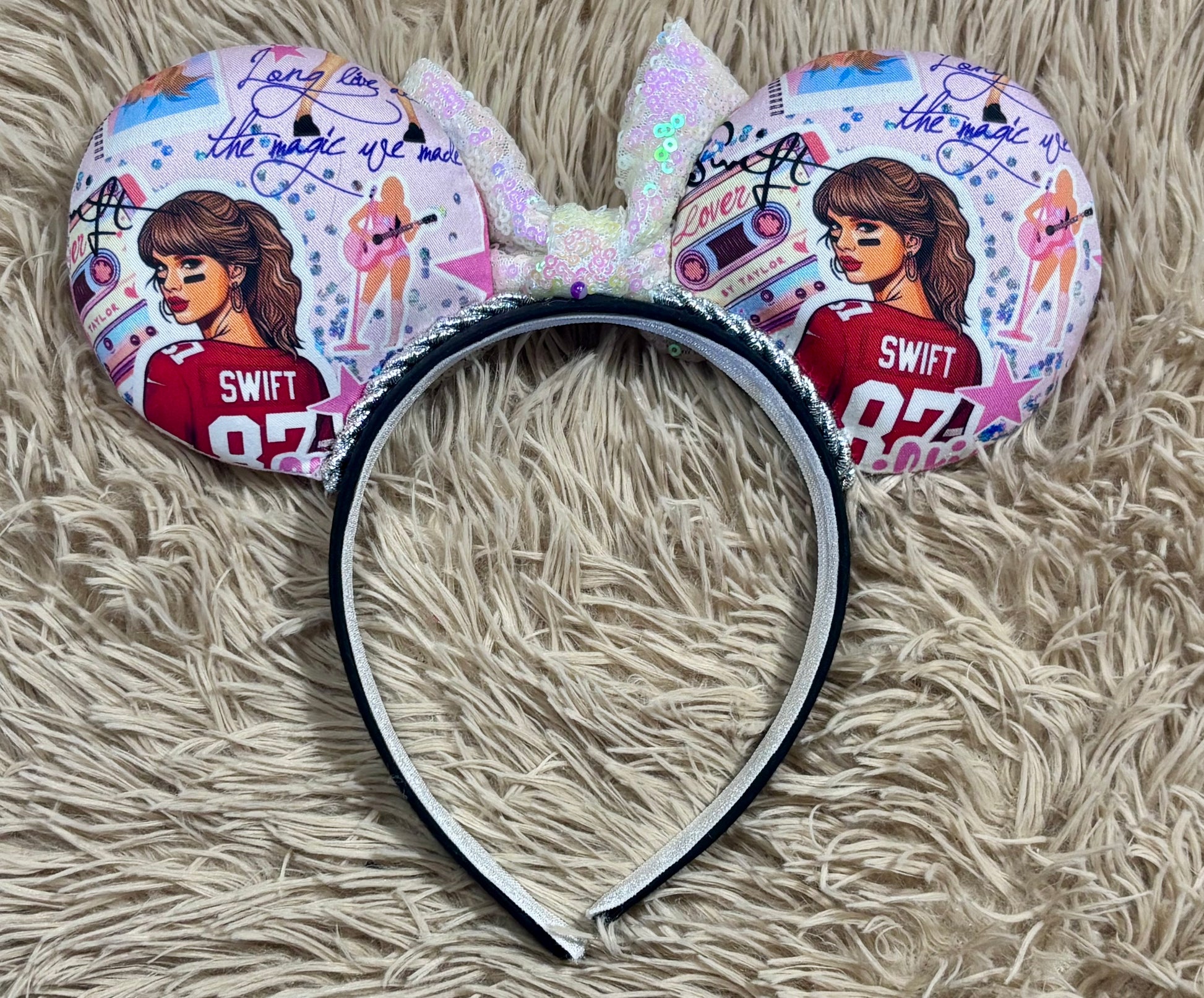 Back view of ear headband with a large iridescent bow and custom printed ears featuring retro cassette graphics, a pink star, and a portrait of singer.