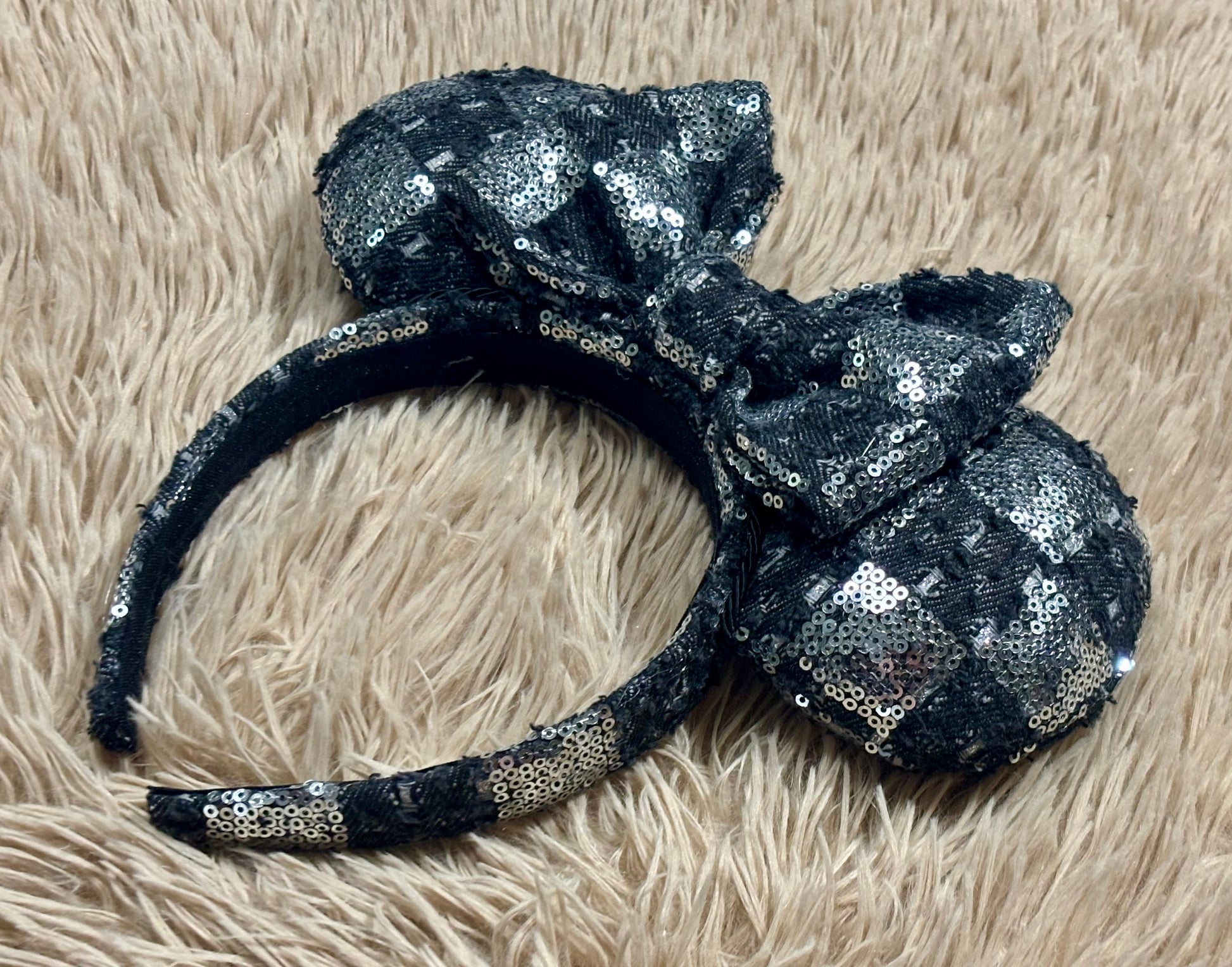 A black and silver checkered sequined headband with large bow ears.