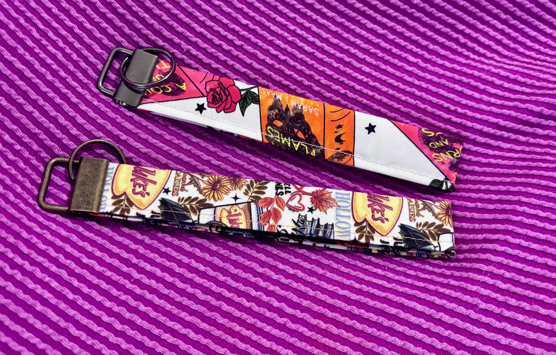 Two colorful keychains with a pattern on a purple striped background
