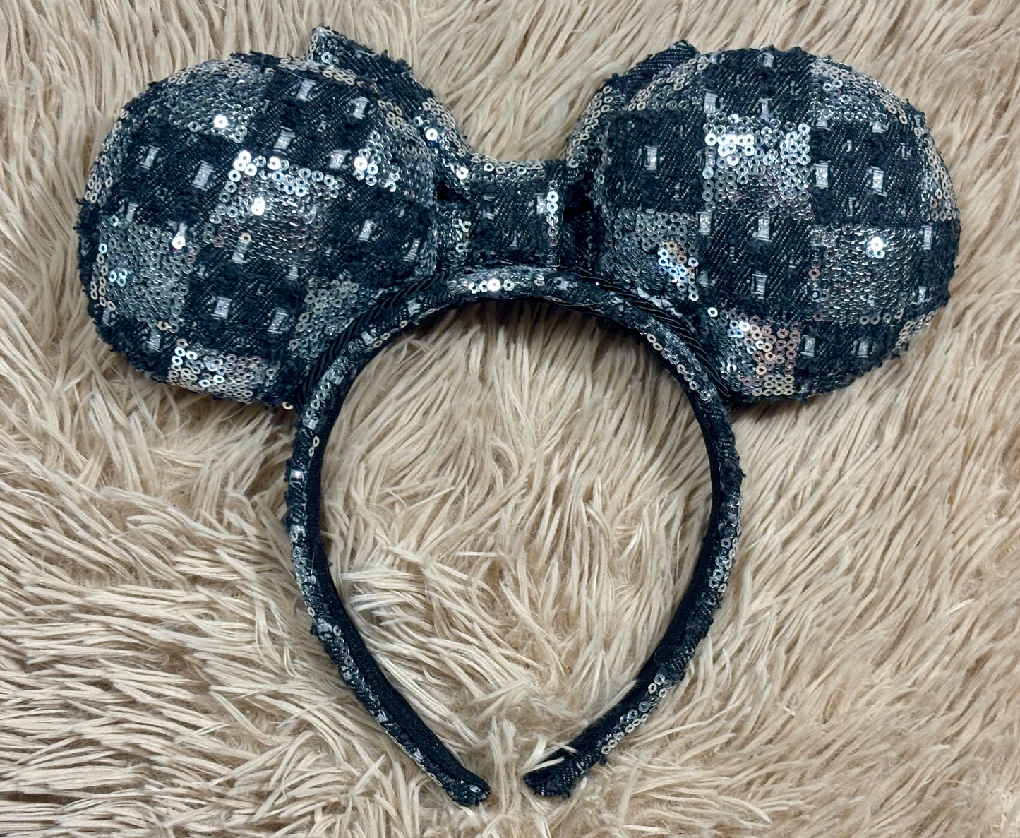 A black and silver checkered sequined headband with large bow ears. The back view of the set of ears.