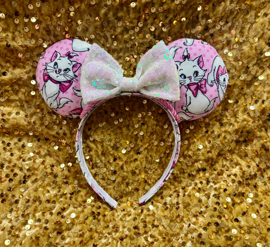 Pink mouse ear headband with white bow shown on a gold glitter background