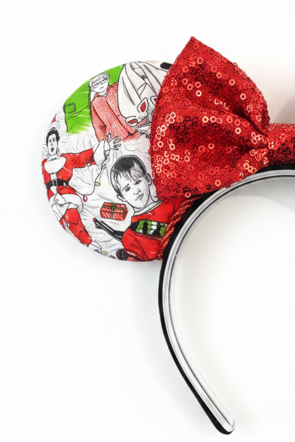 Classic Christmas films inspired fabric on front, back and the headband as well. These are handmade and ready to ship mouse ears with a red sequin bow. Shown on a white background. this is a closeup of some characters such as Kevin from Home Alone and Clark from Christmas vacation,