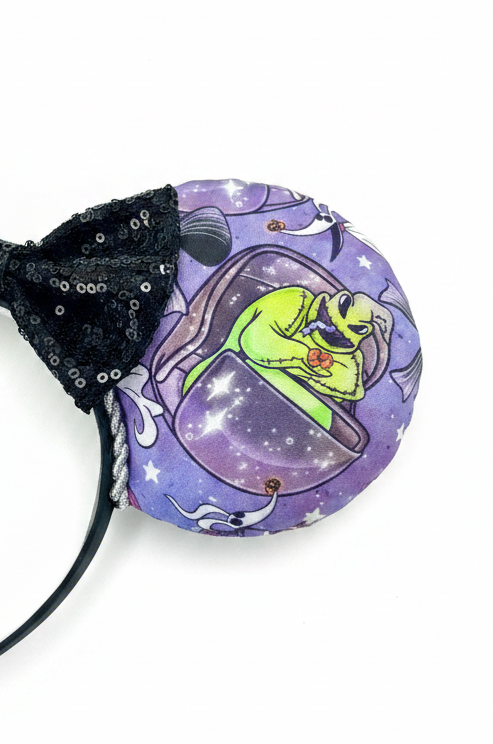 Handmade and ready to ship HM and NBC Mashup mouse ears. The fabric is on both the front and back. The headband is black and lined with white elastic. Shown with a black sequin bow. Item is shown on a white background. Oogie is shown on this side.