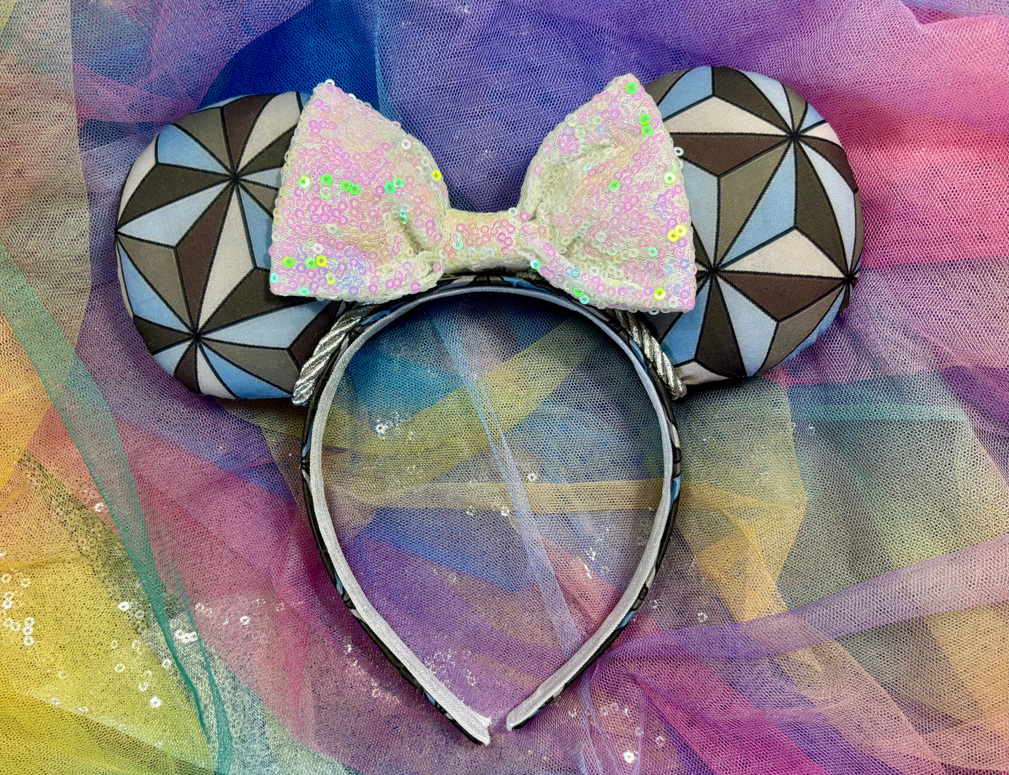 Handmade and ready to ship Mouse ear headband with a geometric design inspired by Spaceship Earth ride and a white iridescent bow on a universal sized black headband.