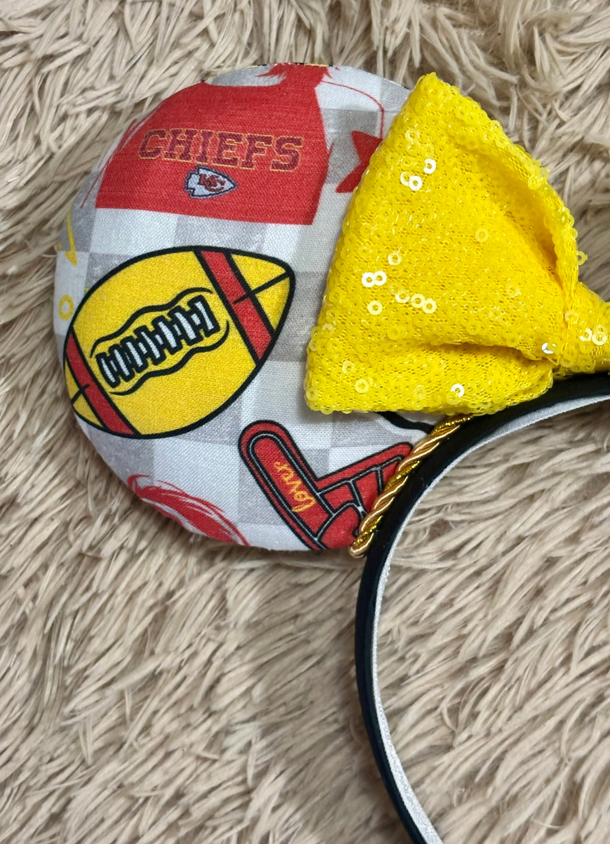 An ear headband featuring a bright yellow sequined bow. The set has TS and Chiefs images on it. Set on a universal sized headband.