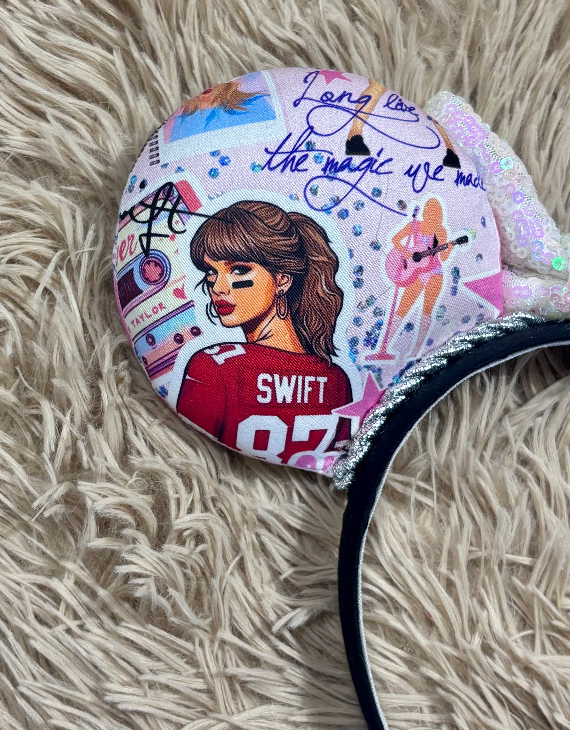 An ear headband with a large iridescent bow and custom printed ears featuring retro cassette graphics, a pink star, and a portrait of singer.