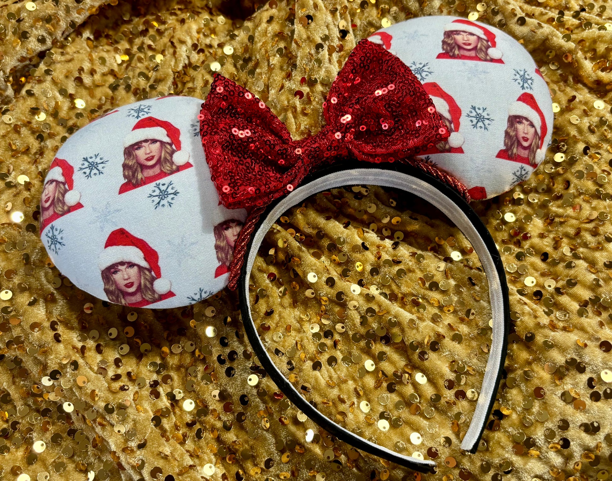 Christmas-themed minnie mouse ears with a red bow on a gold glitter background