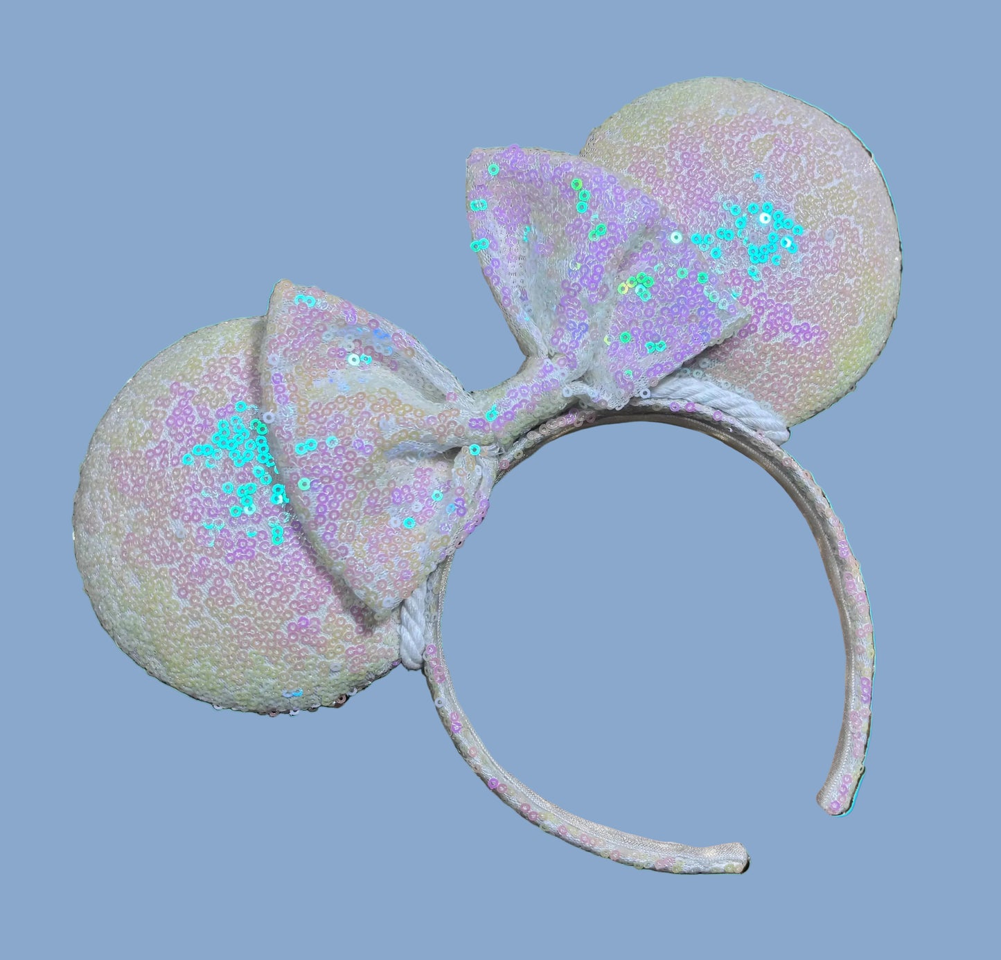 White Iridescent mouse ears with the fabric on both the front and back. The fabric is on the headband as well and is universal sized and fits most. The set has a matching iridescent sequin bow. 