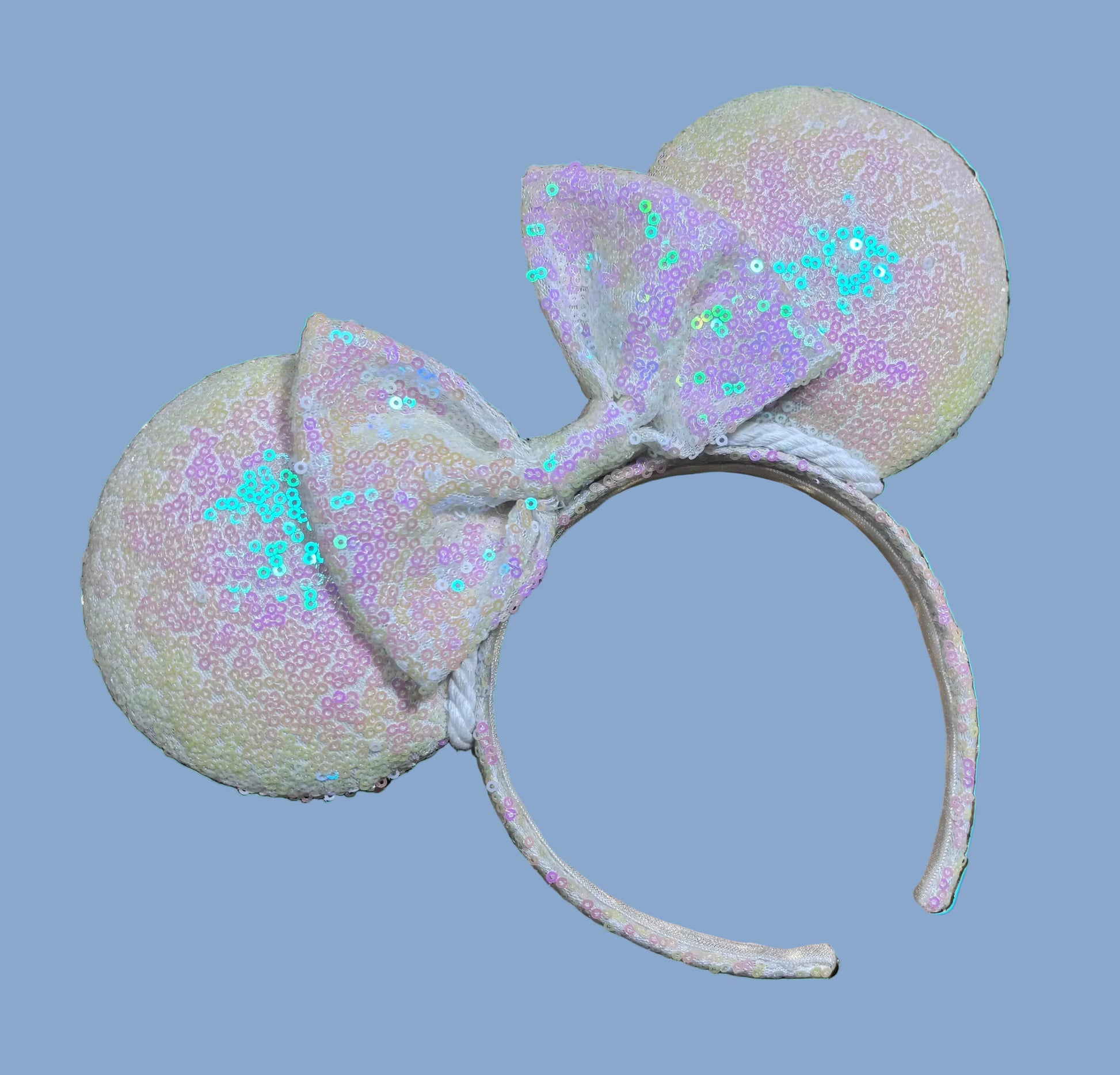 White Iridescent mouse ears with the fabric on both the front and back. The fabric is on the headband as well and is universal sized and fits most. The set has a matching iridescent sequin bow. 