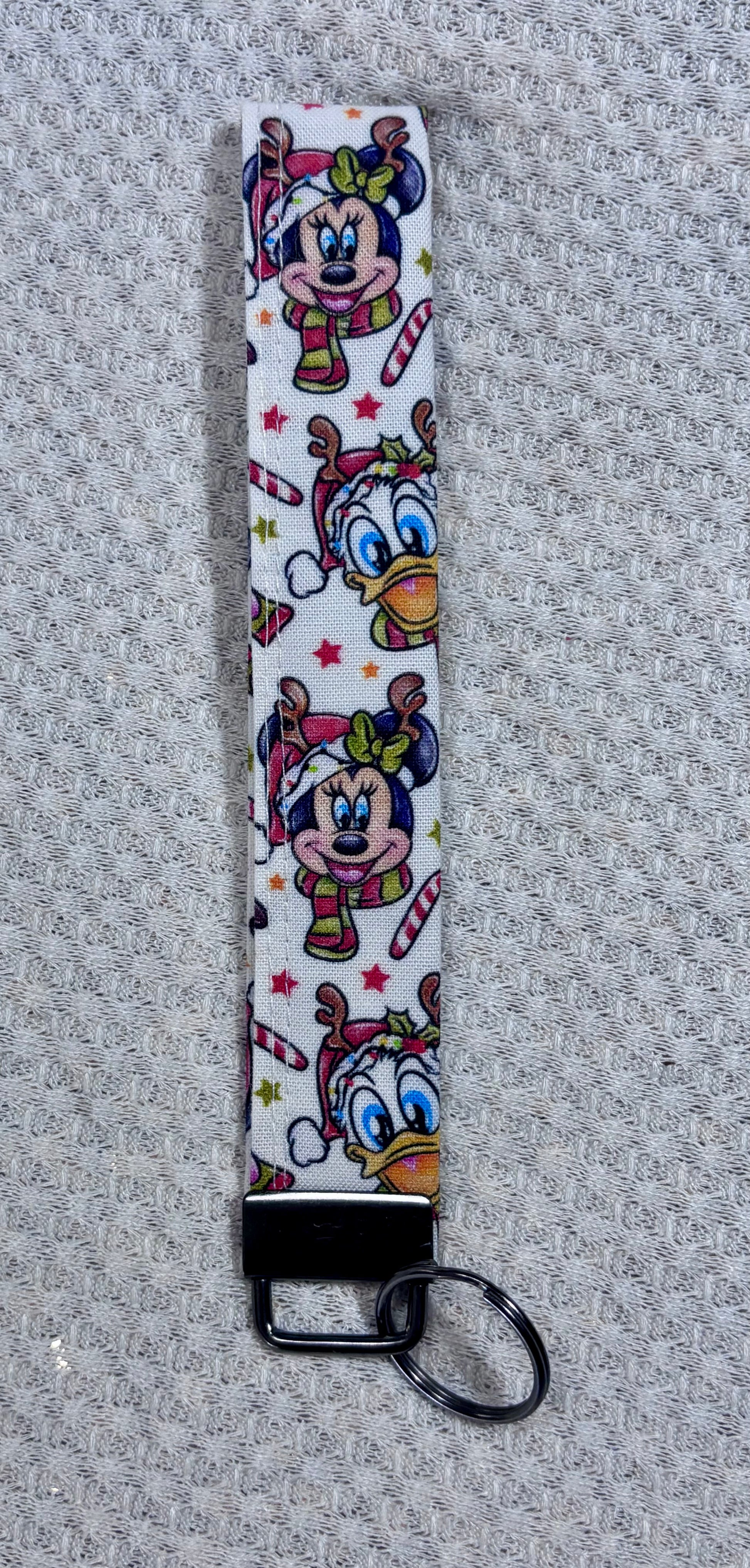 Keychain strap with cartoon character design on a textured gray background