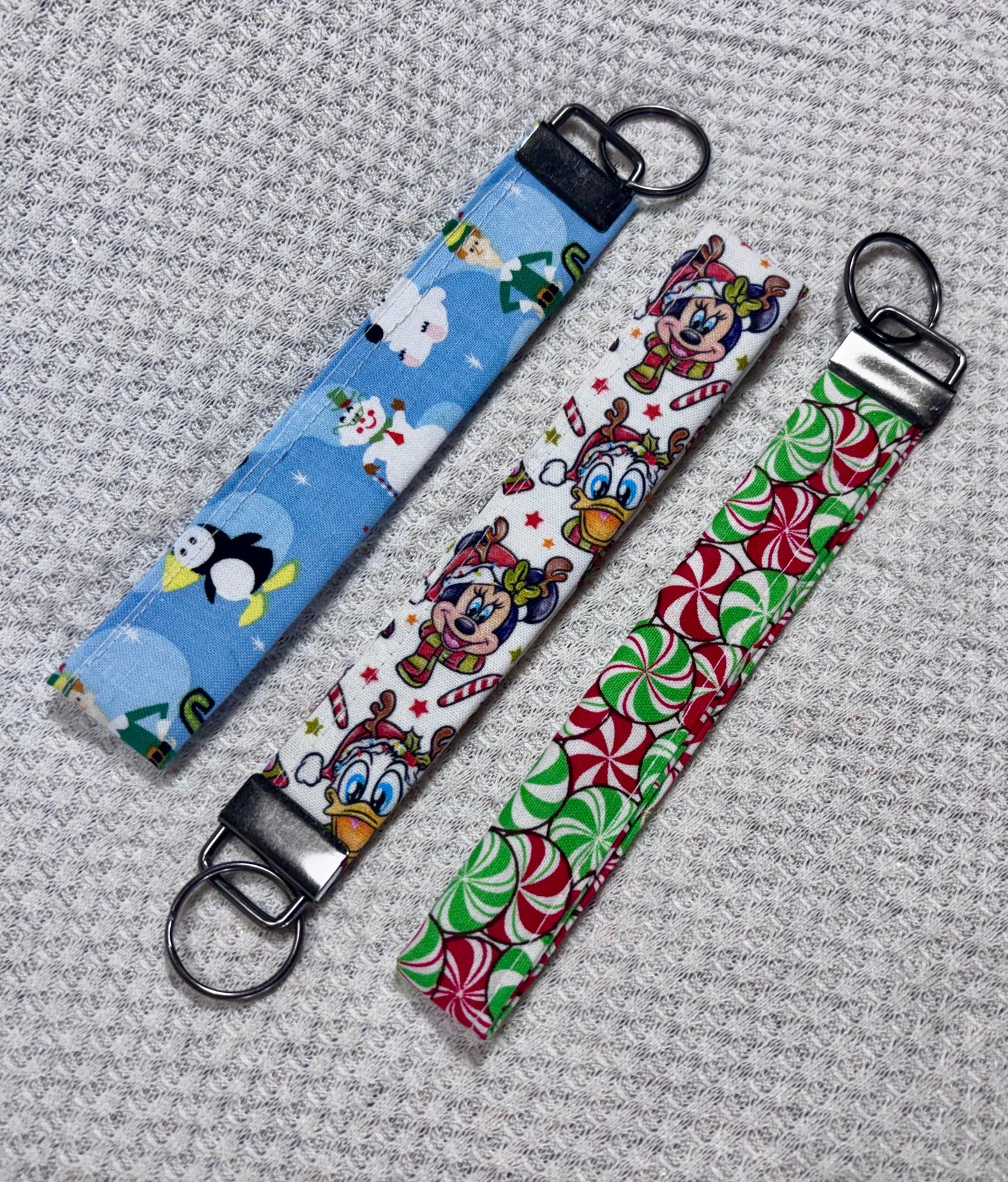 Three fabric keychains with cartoon characters on a textured gray surface