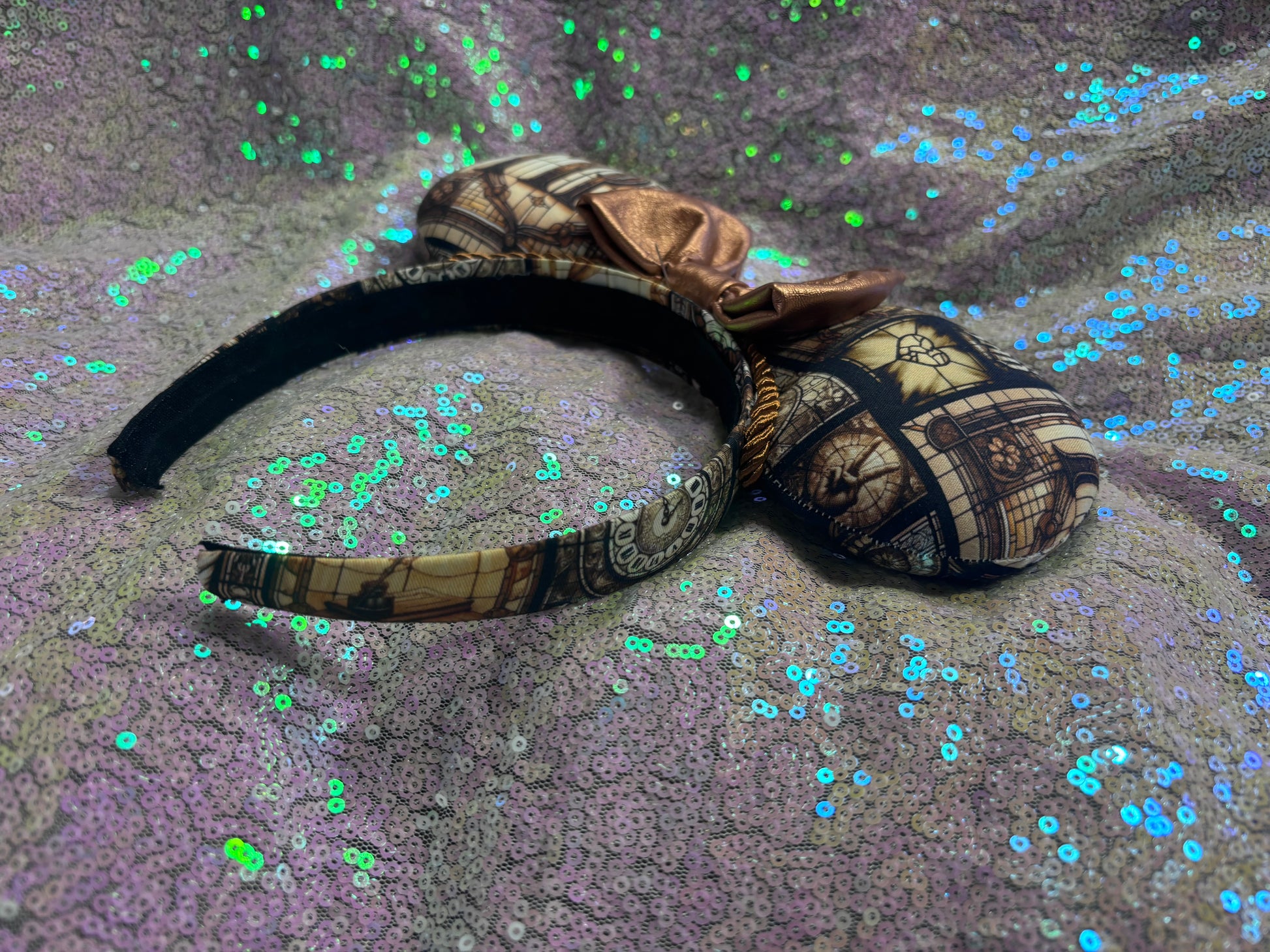 Mouse ears with a rose gold pleather bow and decorative elements on a textured purple background