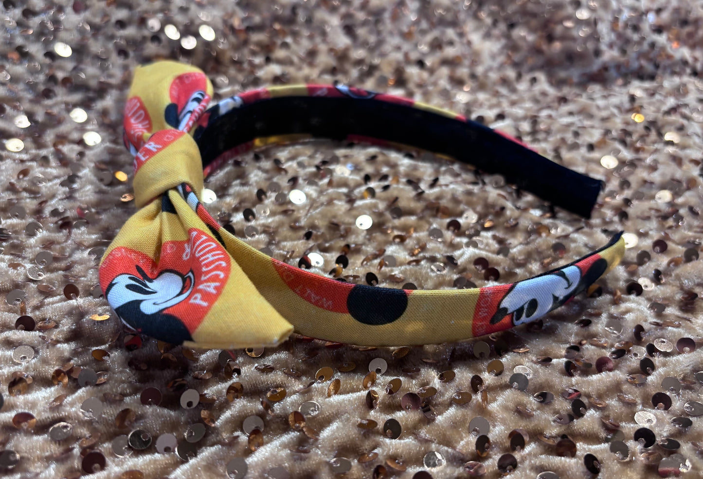Side view of universal sized Colorful headband with a bow on a glittery surface