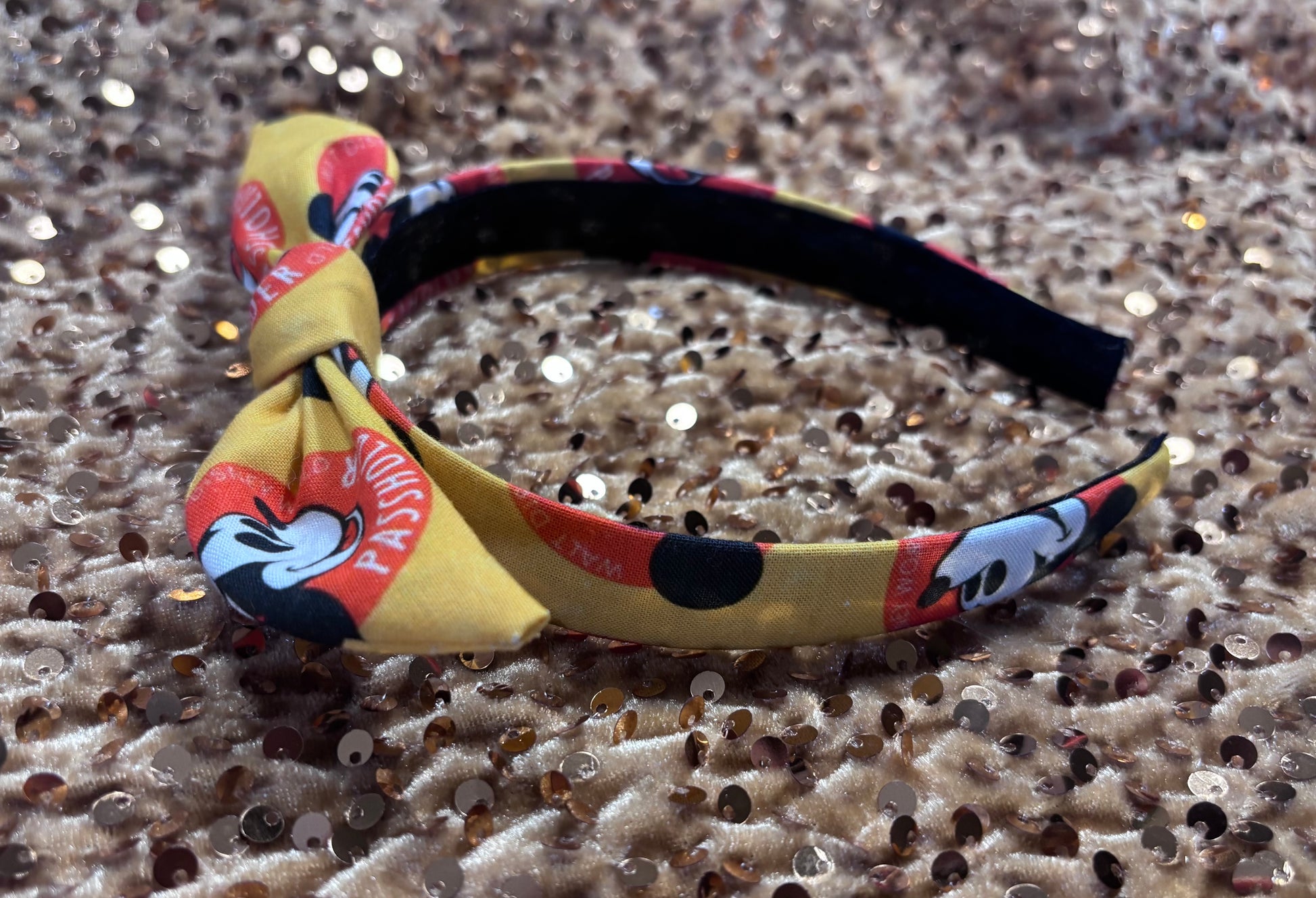 Side view of universal sized Colorful headband with a bow on a glittery surface