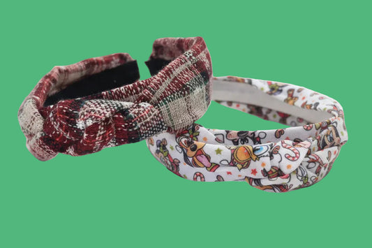 Two handmade twisted knot headbands, one with a plaid with snowflake pattern and the other with Christmas Pals cartoon characters.