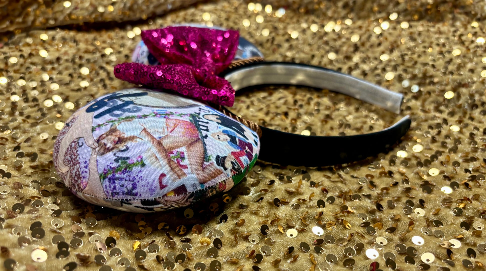 Decorative headband with colorful design and pink bow on a glittery gold background