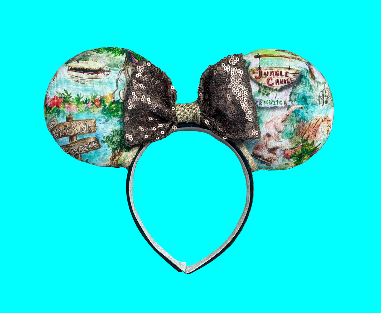 A pair of mouse ears headband featuring a colorful Jungle themed print on the ears and a dark brown sequined bow in the center.