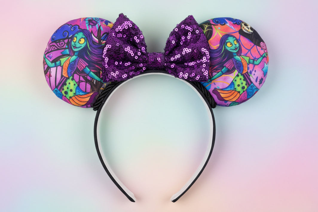 Colorful NBC Sally mouse ears with a purple sequin bow and black twisted trim. Shown on a gradient background