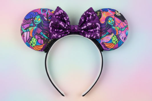 Colorful NBC Sally mouse ears with a purple sequin bow and black twisted trim. Shown on a gradient background