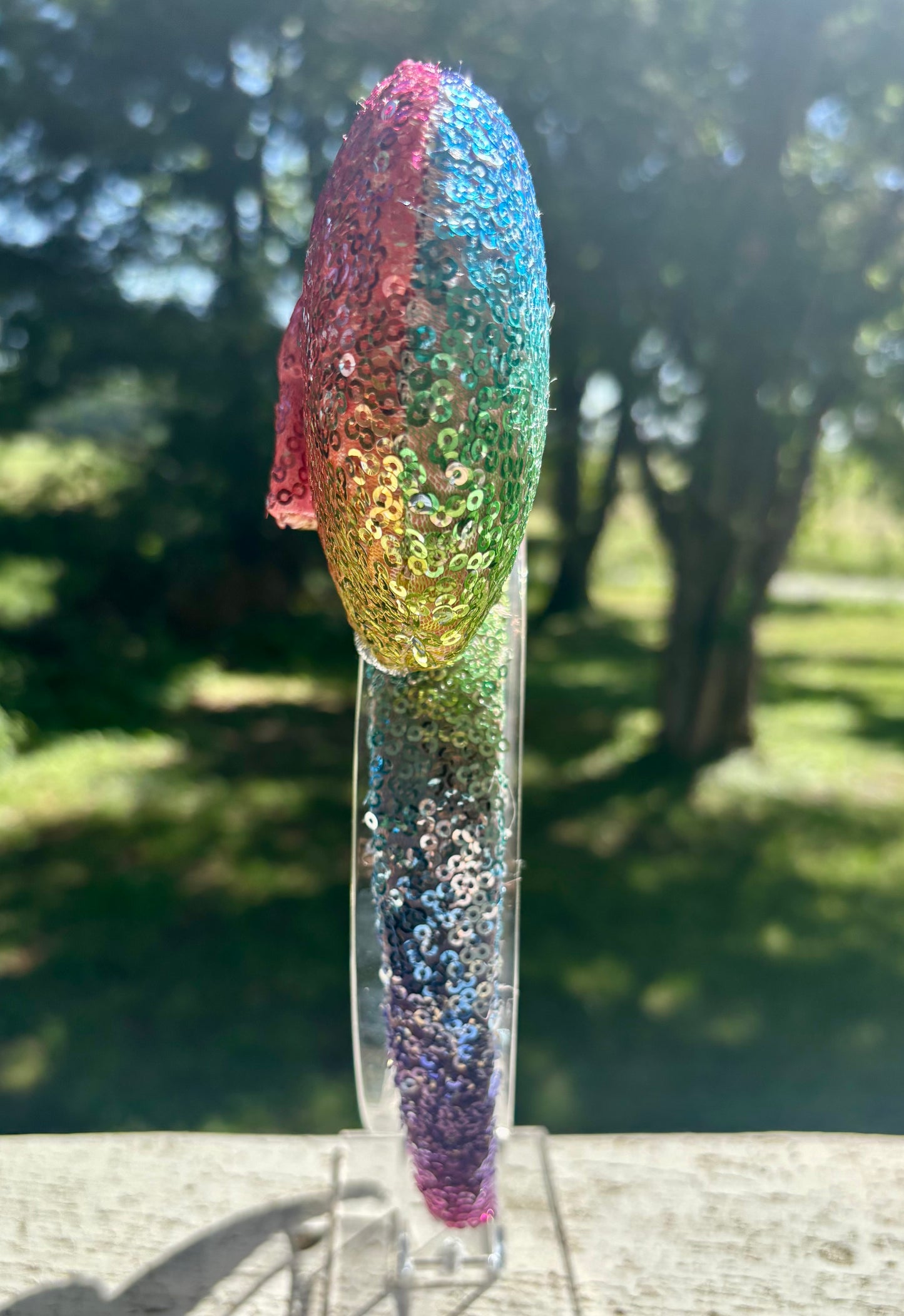 Handmade and ready to ship. Mouse ears with rainbow fabric are on the front and back of mouse ears along with the headband with a matching rainbow sequin bow. Shown on a white background.