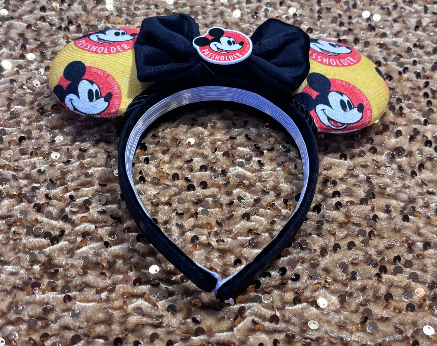 Inner headband view of mouse ears with bow on a glittery gold background