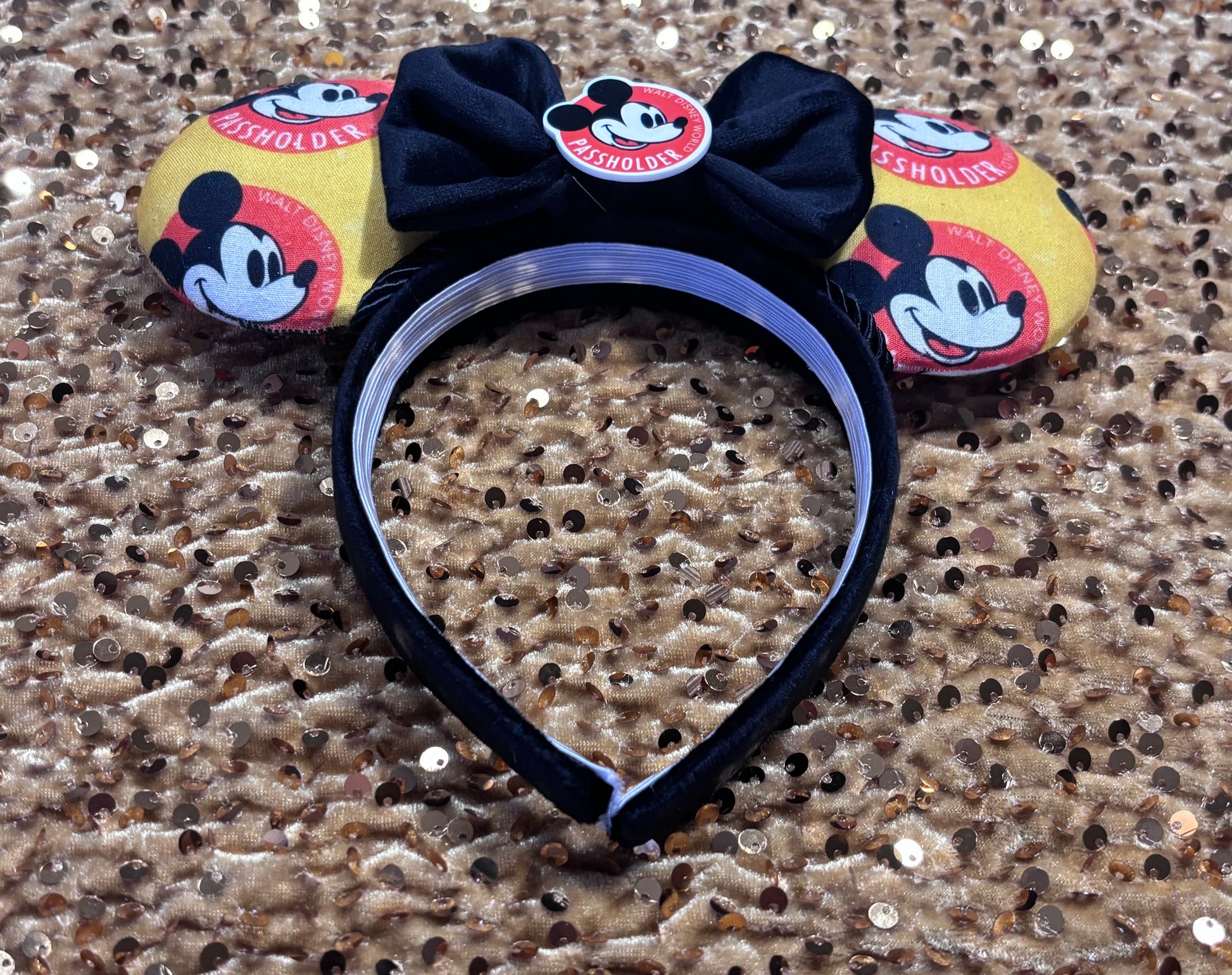 Inner headband view of mouse ears with bow on a glittery gold background