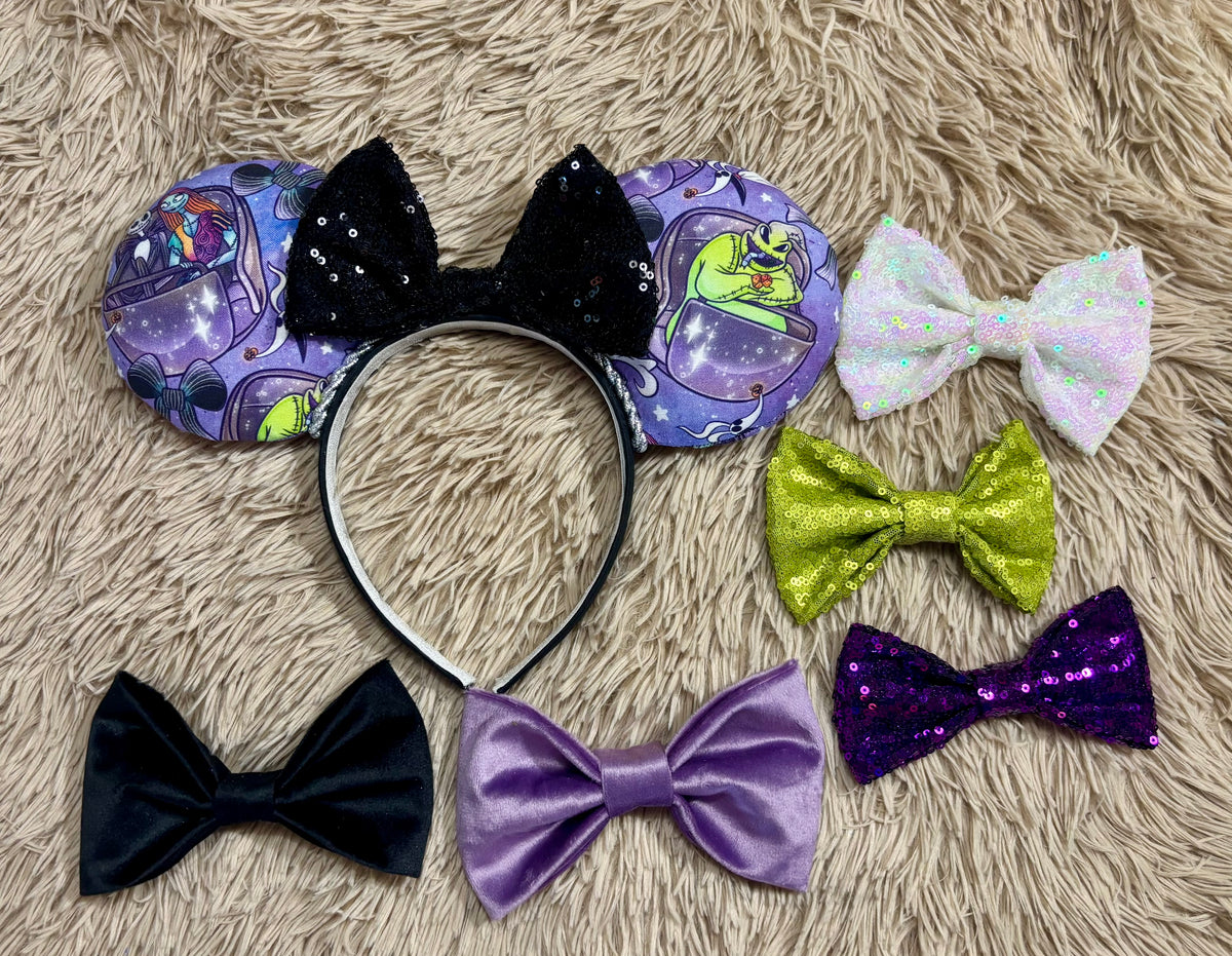 An ear headband accessory with a black sequined bow, featuring a purple HM and NBC themed print with a cartoon character in a buggy. Shown with bow color options in case you don't want the default black sequin bow. Just write me a note in your order of what bow you want and we will happily attach it at no extra charge.