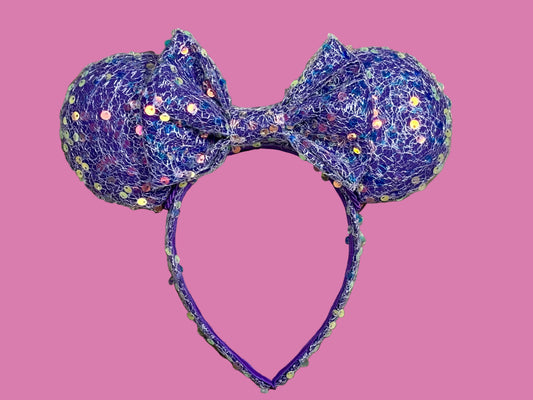 A purple sequined headband with large round ears and a bow, displayed with a purple background.