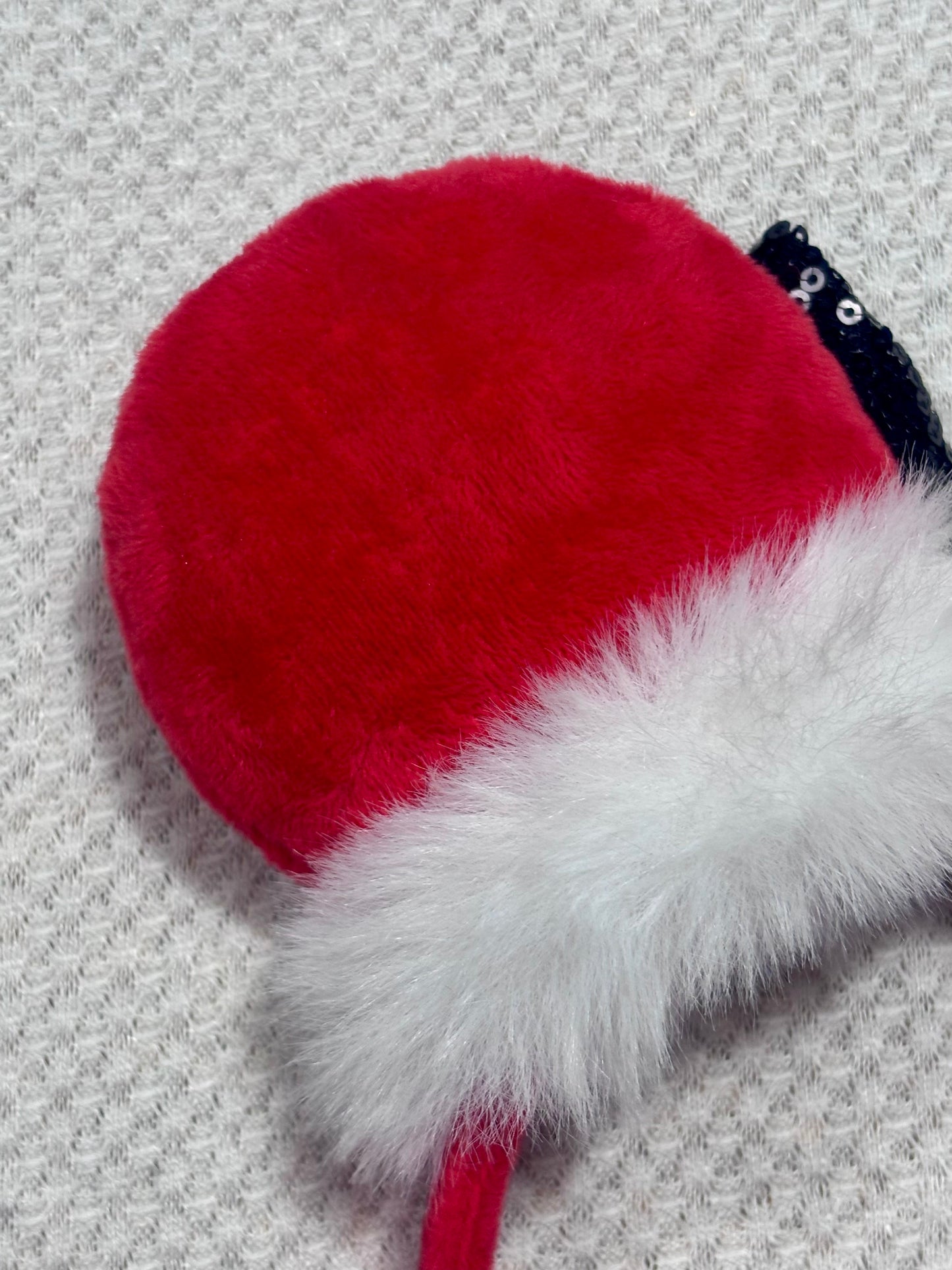 Minnie Mouse ears headband with red plush ears and black bow with gold middle and fluffy white trim on a white background