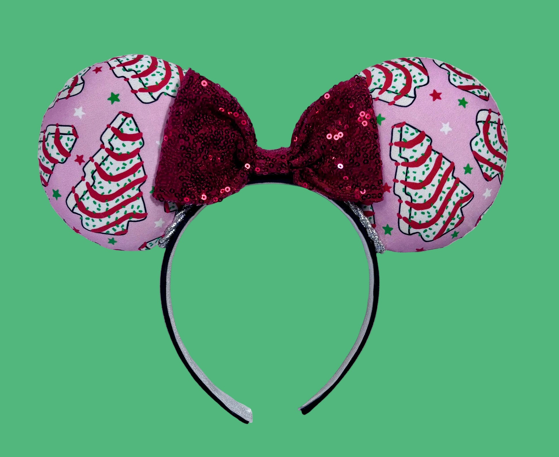 Handmade and ready to ship. Decorative headband with pink fabric and Christmas tree cake inspired fabric on the ears featuring a red sequin bow on a white background