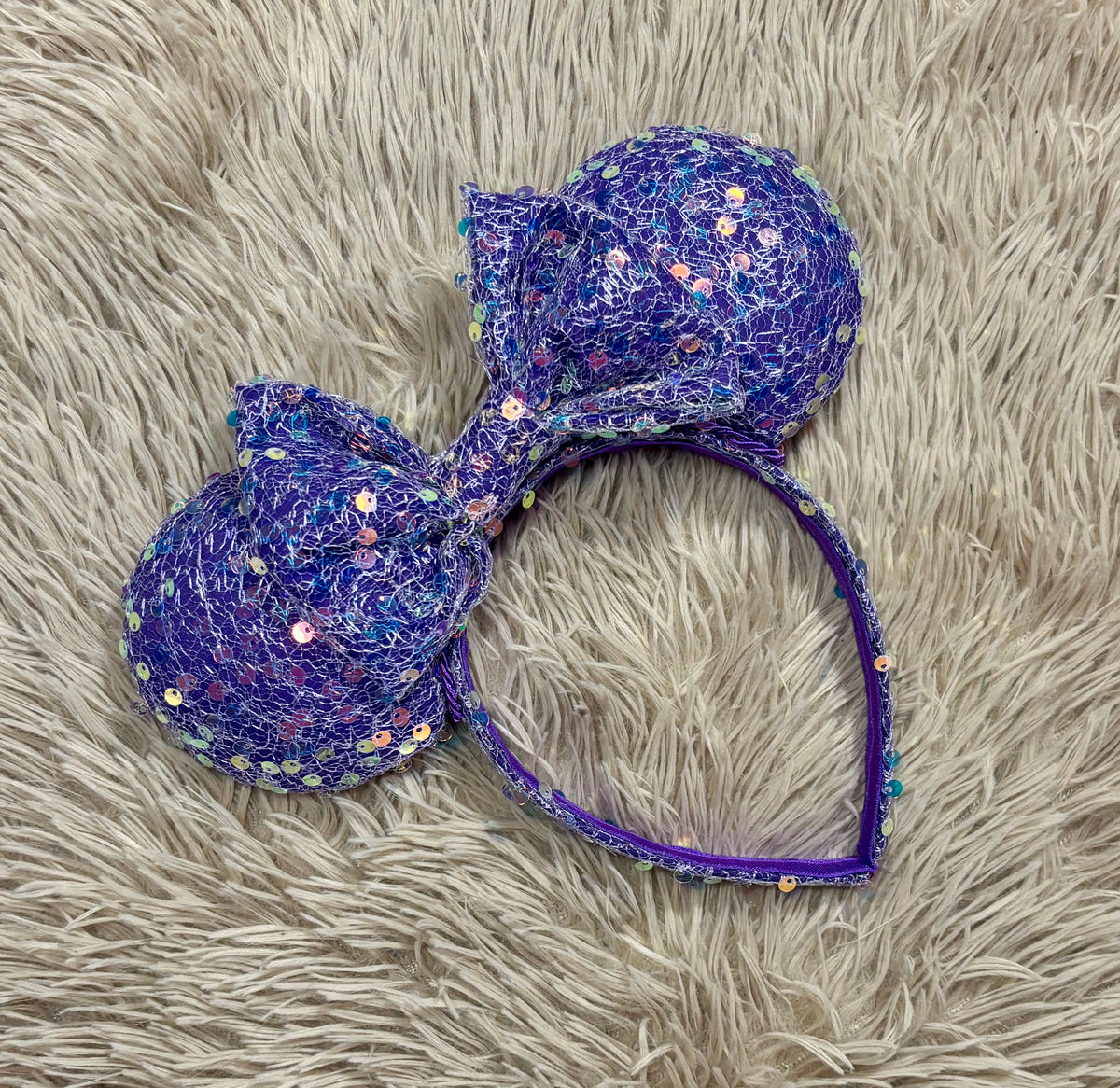 A purple iridescent sequined headband with two large mouse shaped ears.