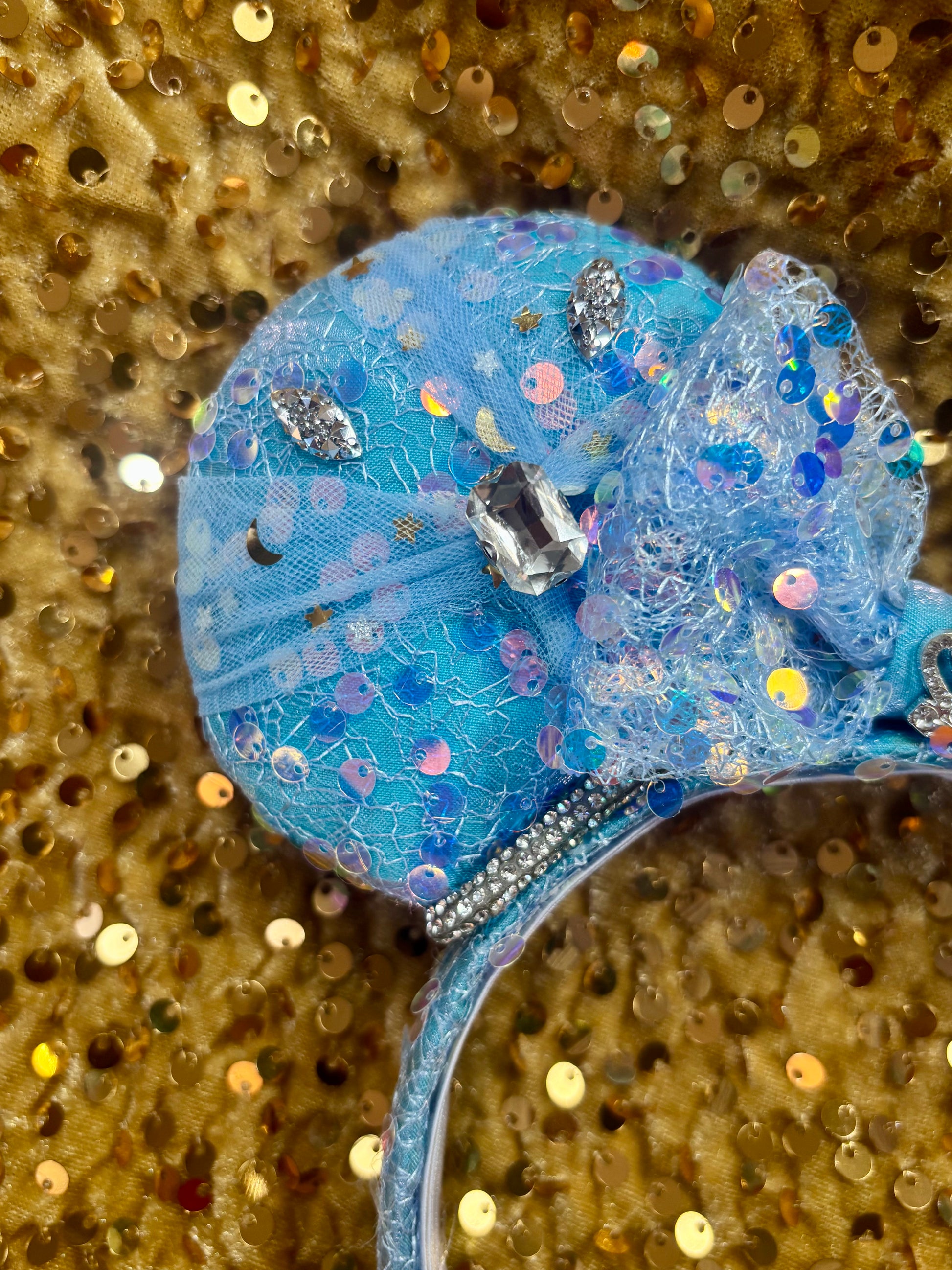 close up of mouse ears with glittery details on a gold sequin background