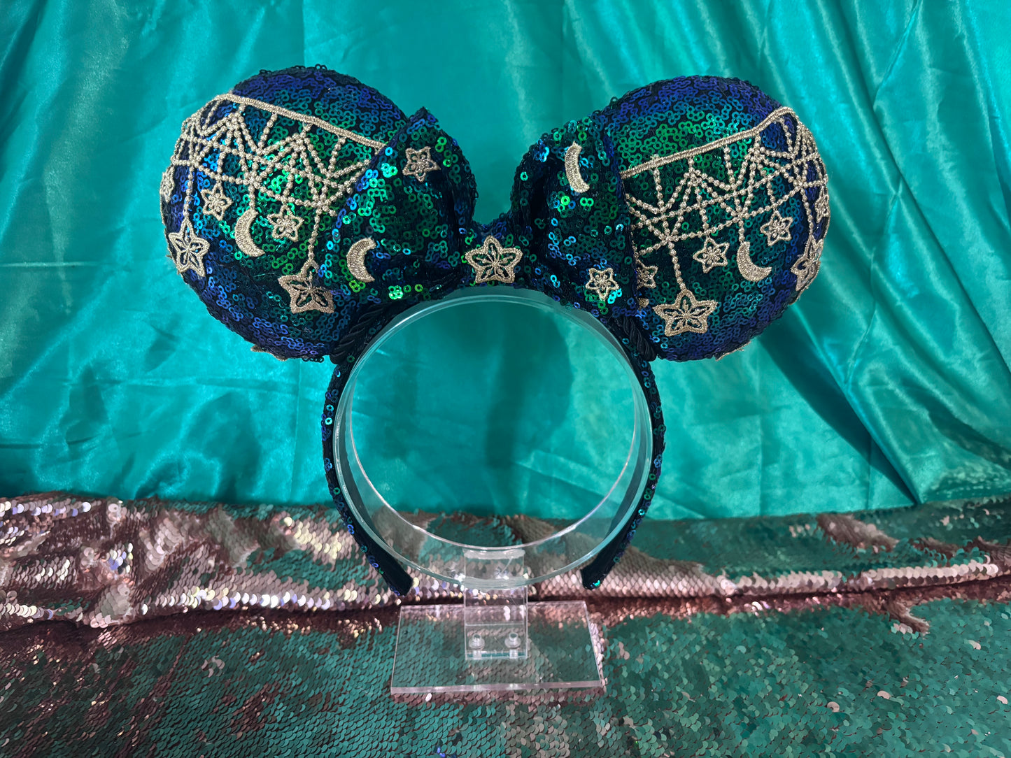 Mouse Ear headband that is a Handmade Iridescent blue and green sequins with gold sun, moon and stars attached to them. bow with star and moon patterns.