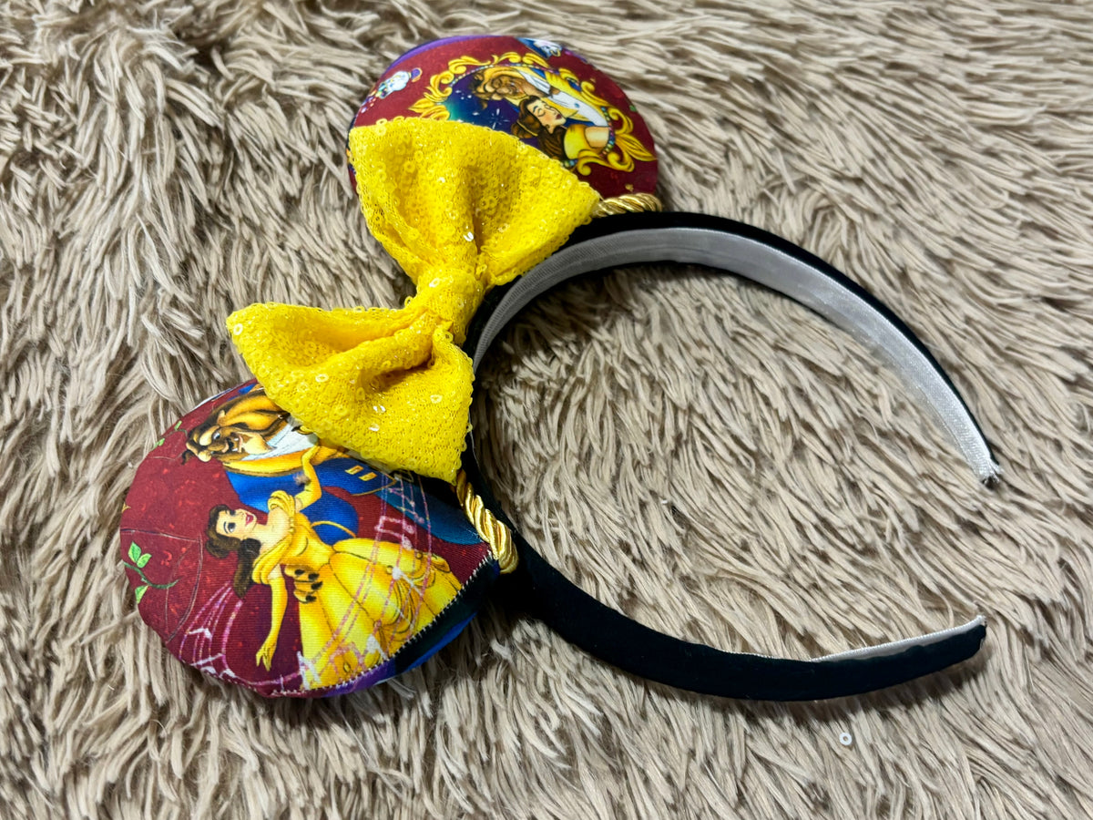Handmade ear headband featuring a large yellow bow and multicolor print with Belle and the Beast.