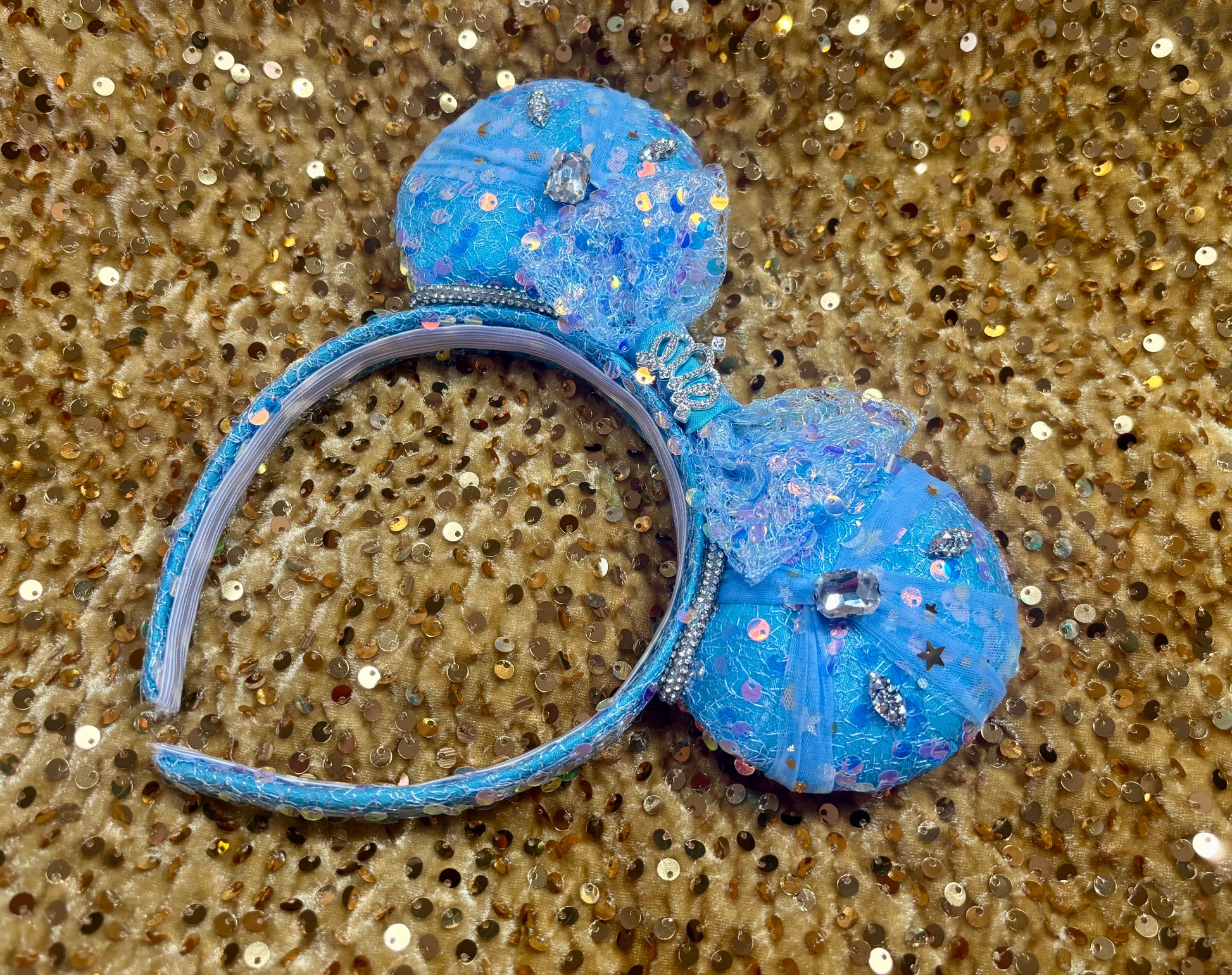 Handmade and ready to ship blue sequin mouse ears headband inspired by Cinderella with tulle and silver gemstones with a crown charm middle and rhinestone trim along inner ears.