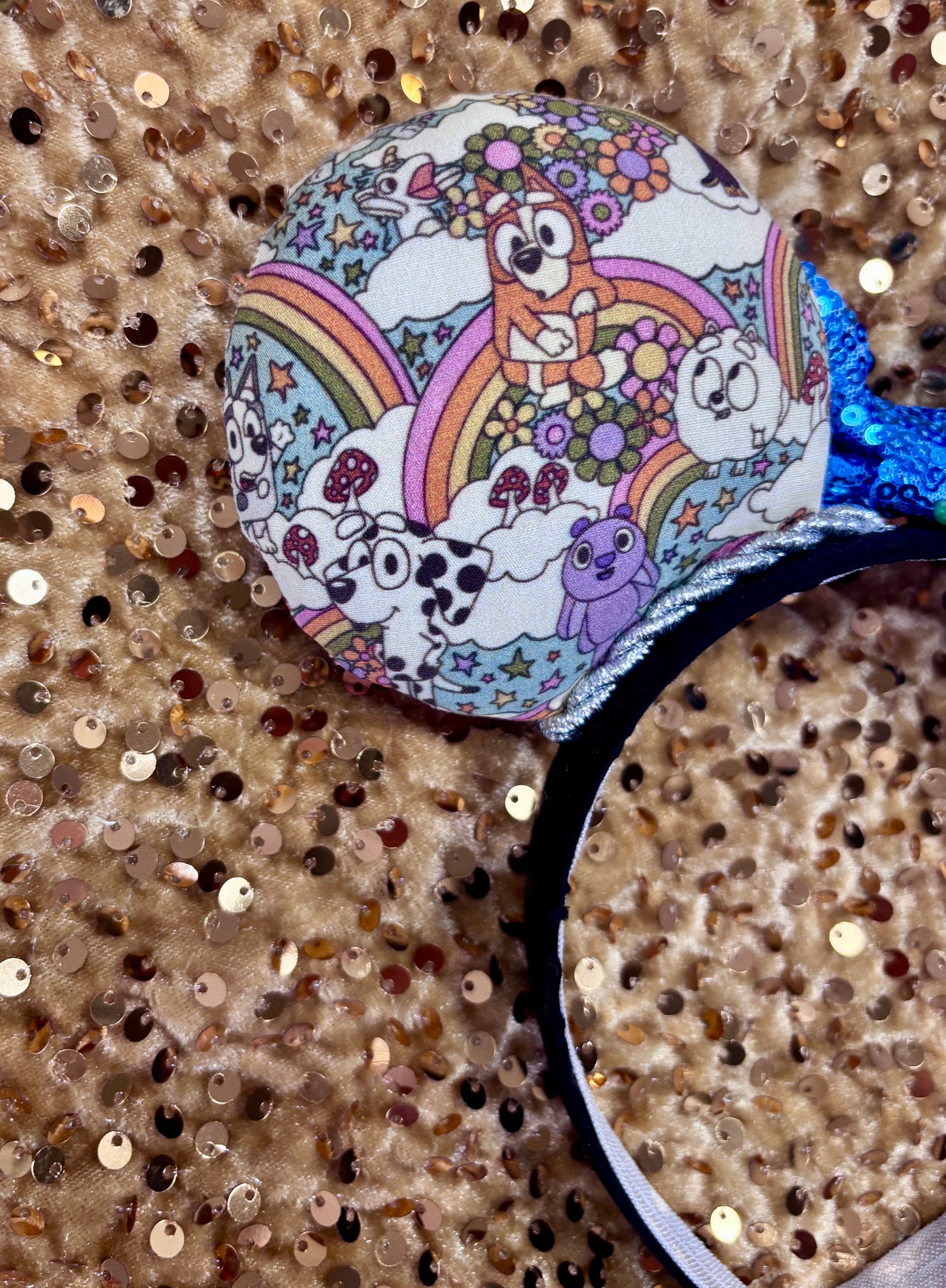 Mouse ears with a blue bow and colorful floral pattern with Bluey and friends on a white background