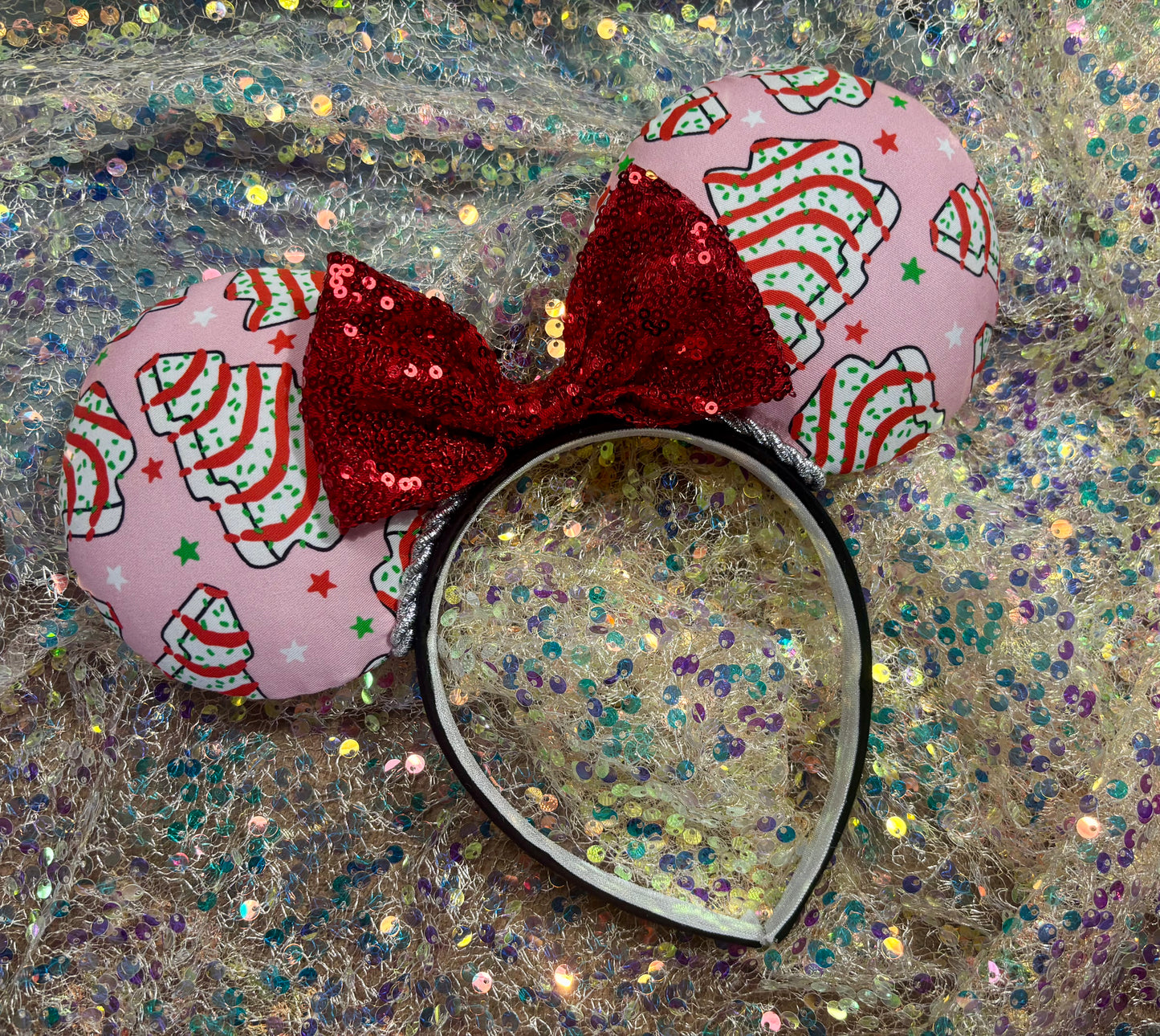 Pink minnie mouse ears with a red bow on a glittery background.