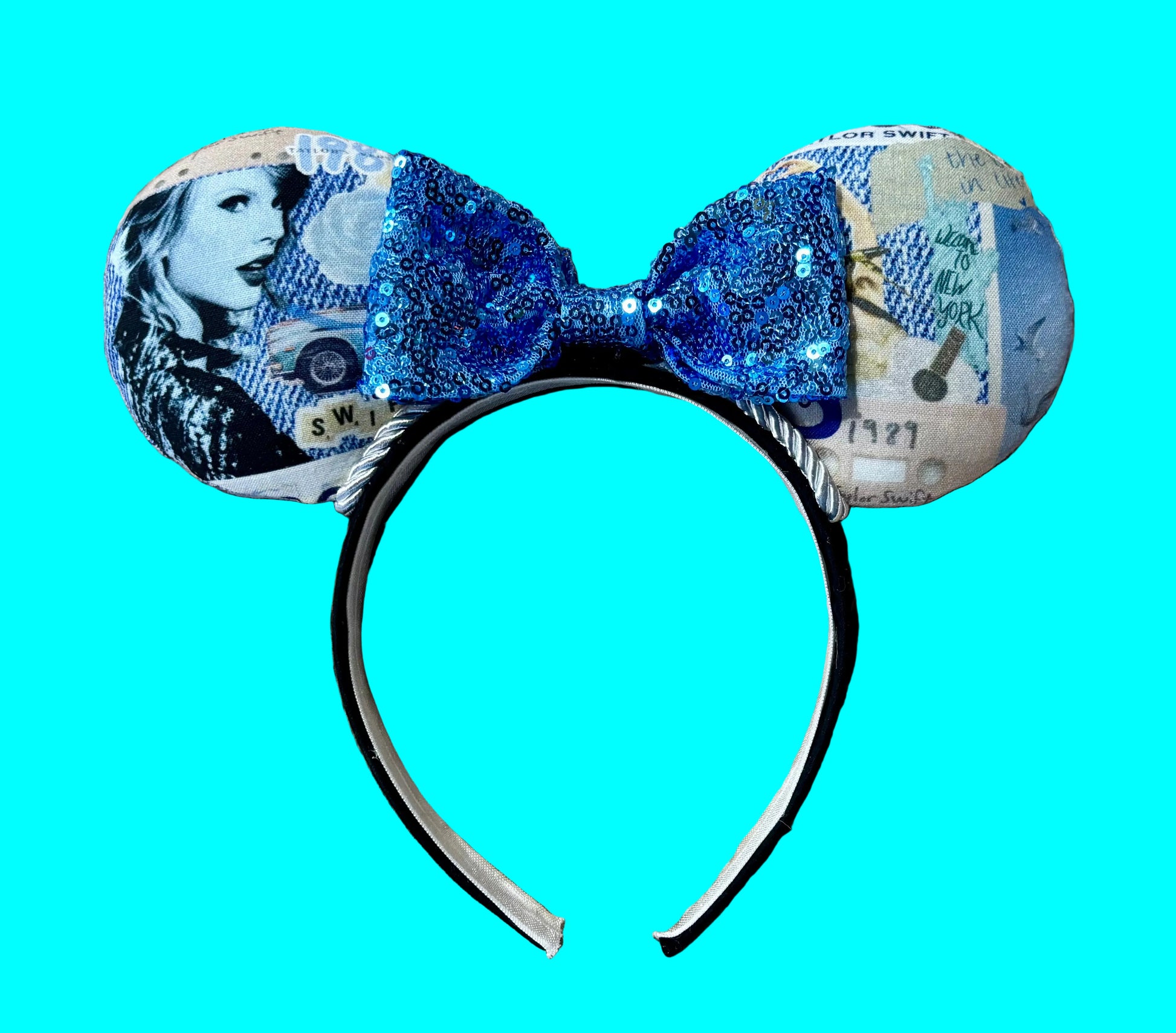 A pair of ears headband accessories featuring a blue sequined bow and ears printed with blue-toned collage artwork