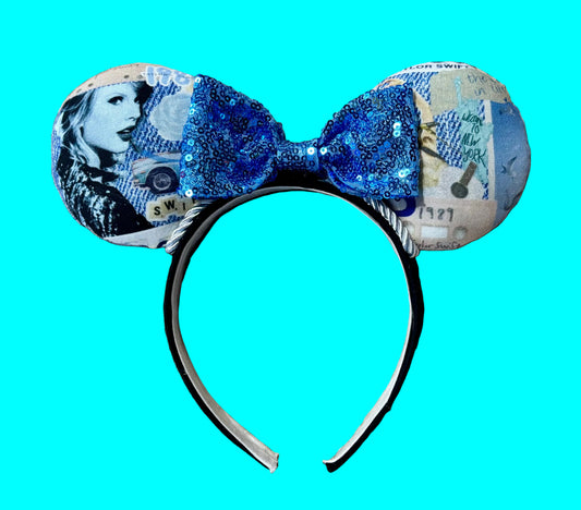 A pair of ears headband accessories featuring a blue sequined bow and ears printed with blue-toned collage artwork